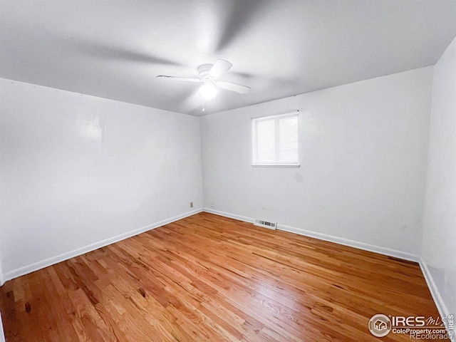 unfurnished room featuring light wood-type flooring, visible vents, baseboards, and a ceiling fan