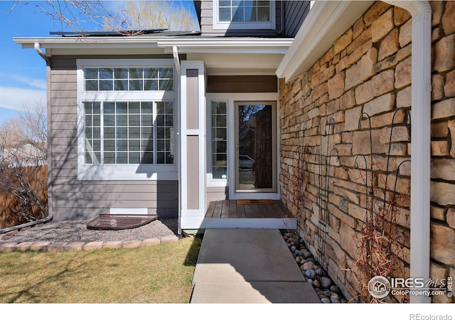 view of exterior entry with solar panels and stone siding