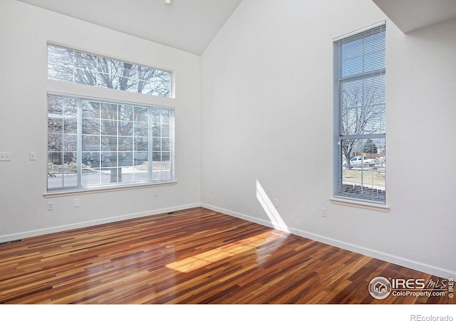 empty room with visible vents, a healthy amount of sunlight, and wood finished floors