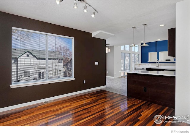 interior space with a textured ceiling, wood finished floors, baseboards, and a sink