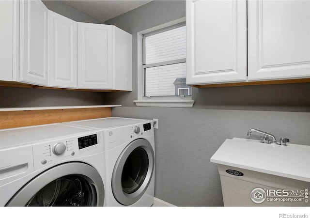 laundry area with cabinet space, washing machine and dryer, and a textured wall