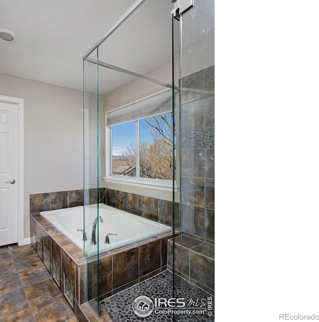 bathroom featuring a bath and a tile shower