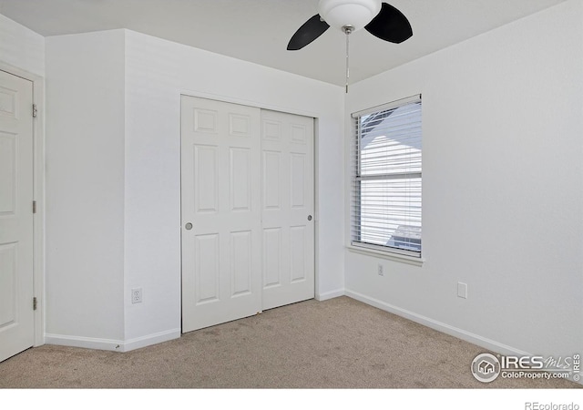 unfurnished bedroom with a closet, carpet flooring, a ceiling fan, and baseboards