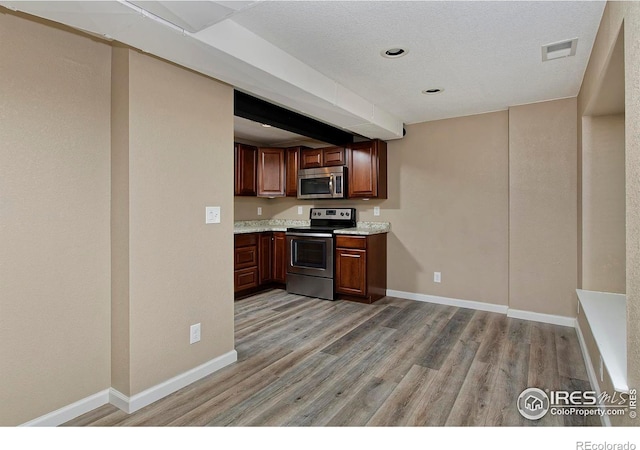 kitchen featuring visible vents, light wood finished floors, stainless steel appliances, light countertops, and baseboards