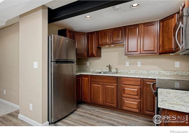 kitchen with a sink, stainless steel appliances, light countertops, and light wood finished floors