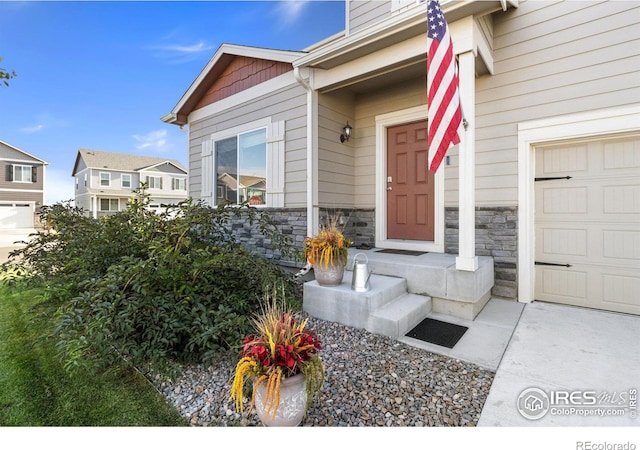 entrance to property with a garage and stone siding