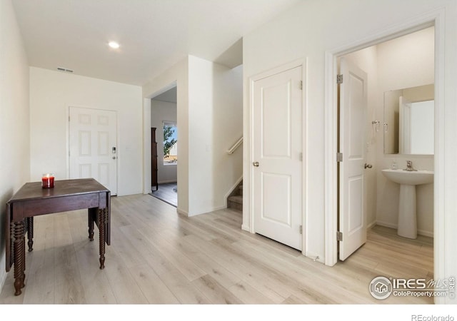 hall featuring visible vents, stairs, and light wood-type flooring