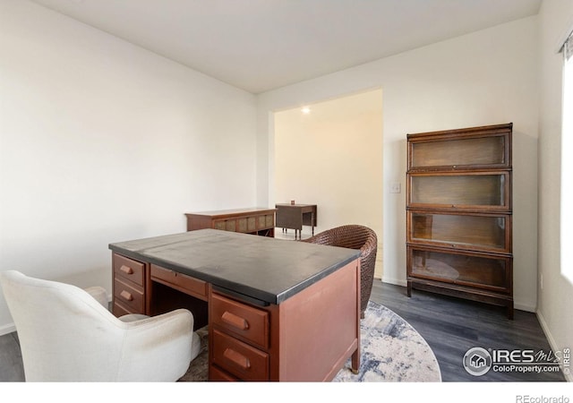 home office with dark wood-type flooring and baseboards