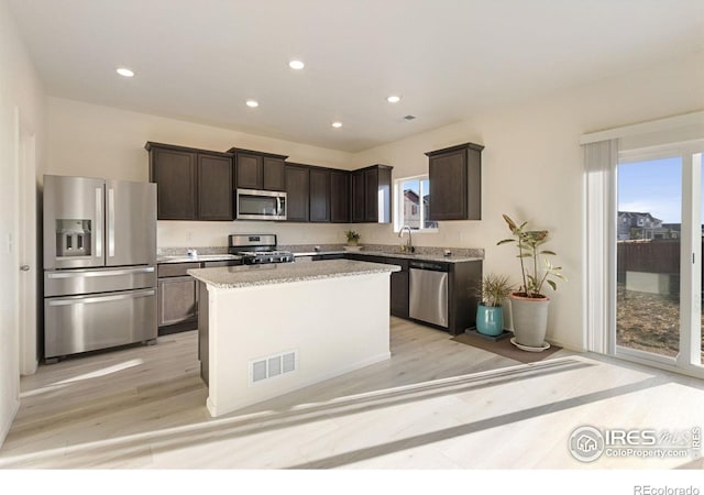 kitchen featuring visible vents, a kitchen island, dark brown cabinetry, and appliances with stainless steel finishes