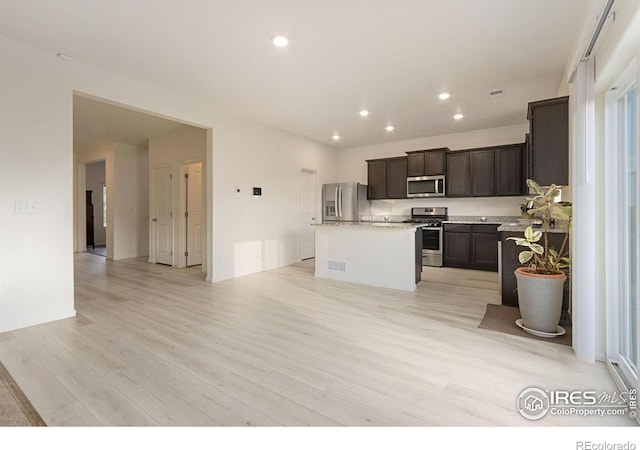 kitchen with light wood finished floors, a kitchen island, dark brown cabinetry, recessed lighting, and stainless steel appliances