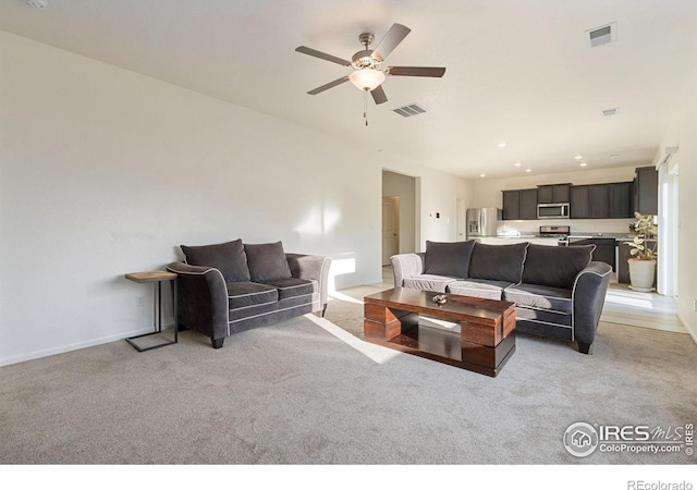 living room with baseboards, a ceiling fan, visible vents, and light carpet