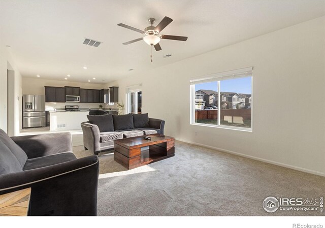 living room with a ceiling fan, visible vents, baseboards, recessed lighting, and light colored carpet