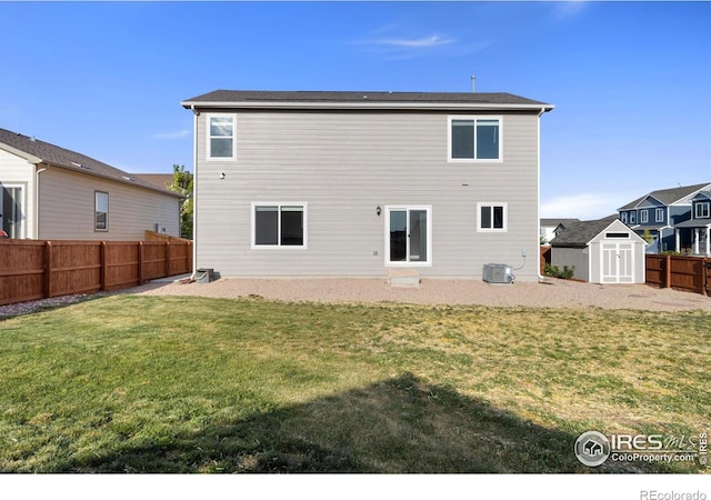 rear view of property featuring a shed, central AC unit, a lawn, a fenced backyard, and an outdoor structure