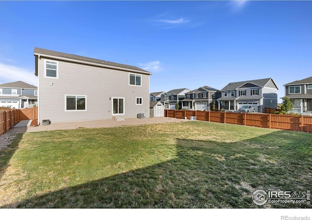 rear view of property featuring a residential view, a lawn, a shed, and a fenced backyard