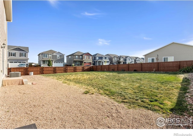 view of yard featuring a residential view, central AC unit, and fence