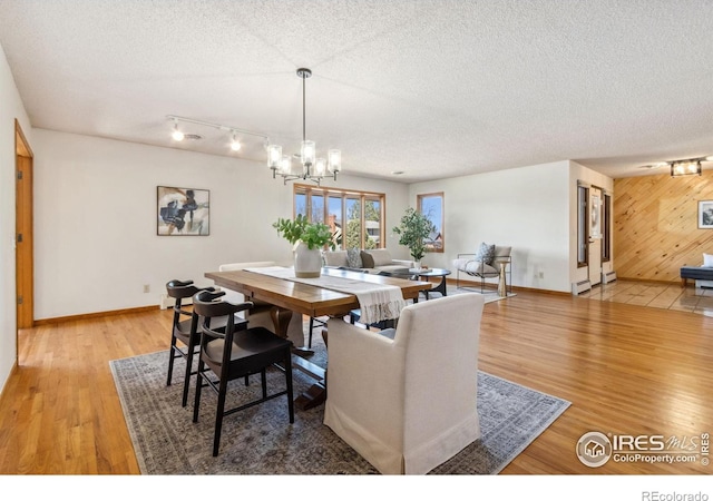 dining room with an inviting chandelier, light wood-style flooring, baseboards, and a textured ceiling