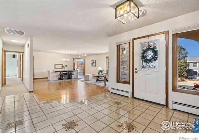 entrance foyer with light tile patterned floors, visible vents, and a baseboard radiator