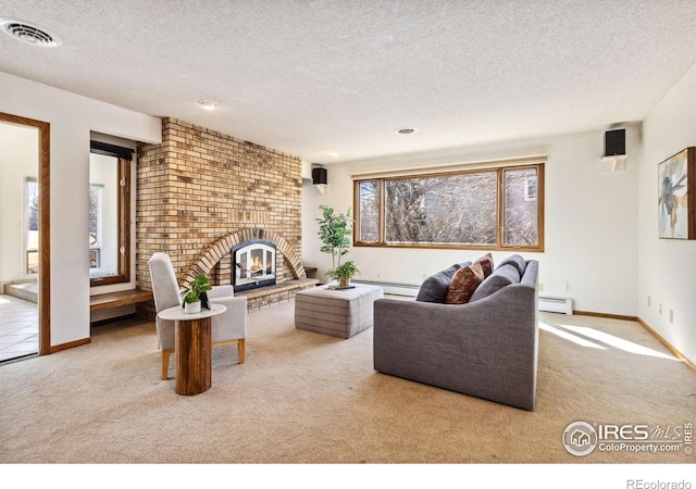 carpeted living area with visible vents, a textured ceiling, a baseboard heating unit, a brick fireplace, and baseboard heating