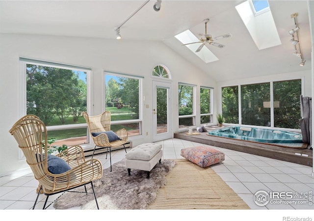 sunroom / solarium featuring track lighting, vaulted ceiling with skylight, and a baseboard radiator