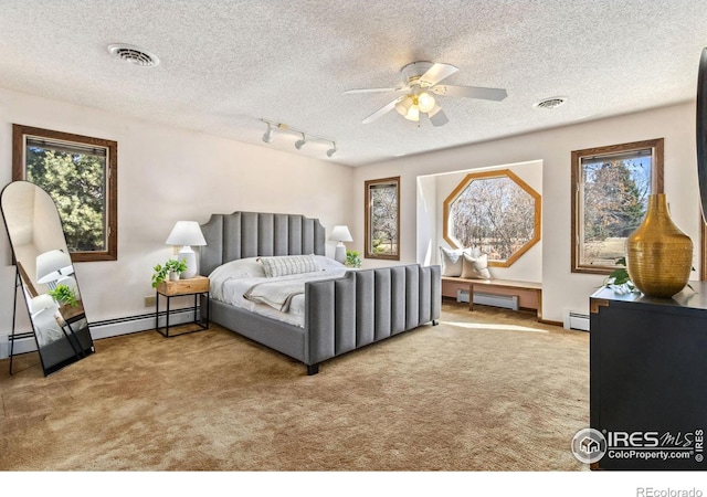 bedroom with a baseboard heating unit, carpet, and visible vents