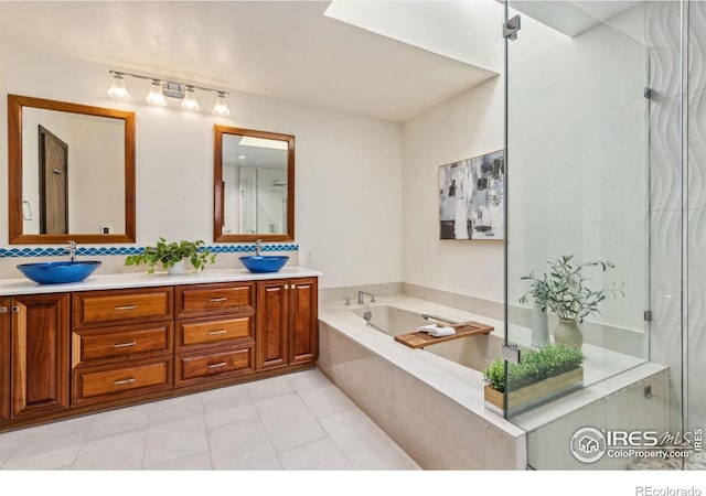 bathroom featuring a sink, a bath, double vanity, and tile patterned floors