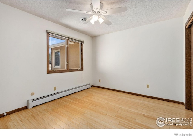 spare room featuring visible vents, light wood-style flooring, a ceiling fan, a textured ceiling, and a baseboard radiator