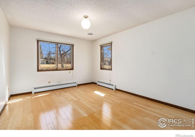 unfurnished room with baseboards, visible vents, wood-type flooring, and a baseboard radiator