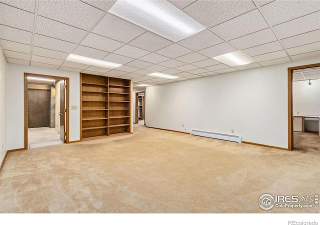 finished below grade area featuring a paneled ceiling, carpet, baseboards, and a baseboard radiator