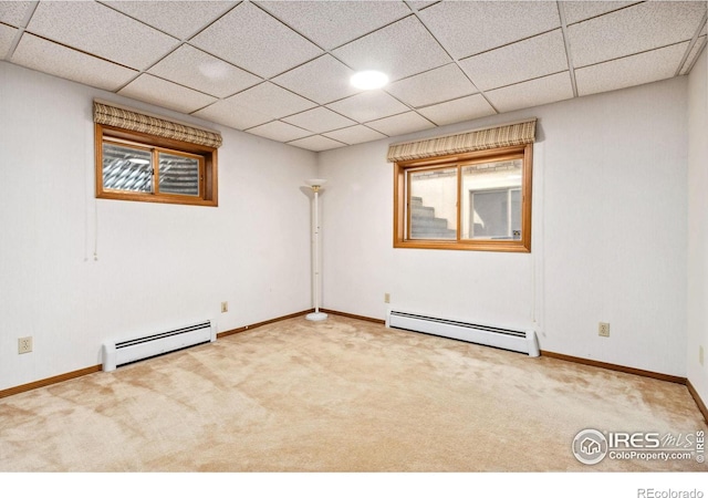 carpeted spare room featuring baseboard heating, baseboards, and a drop ceiling