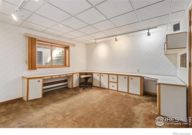 basement with track lighting, carpet, a drop ceiling, baseboard heating, and built in study area