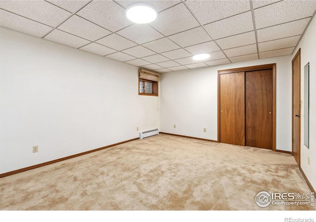 unfurnished bedroom featuring baseboards, a paneled ceiling, a closet, carpet flooring, and baseboard heating