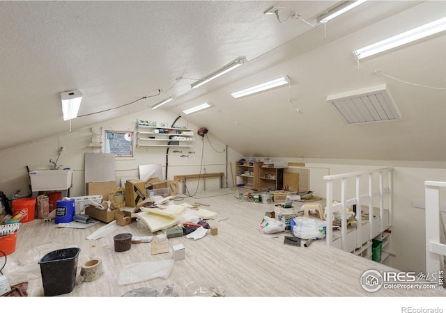 interior space with a sink, lofted ceiling, and a textured ceiling