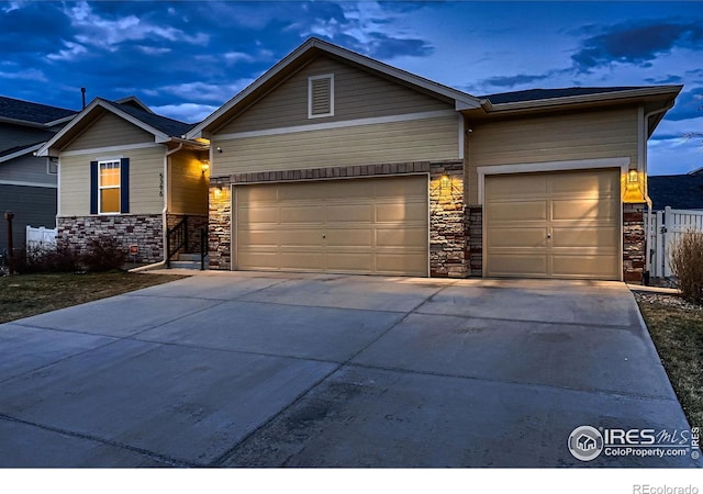 view of front of house with concrete driveway, a garage, fence, and stone siding