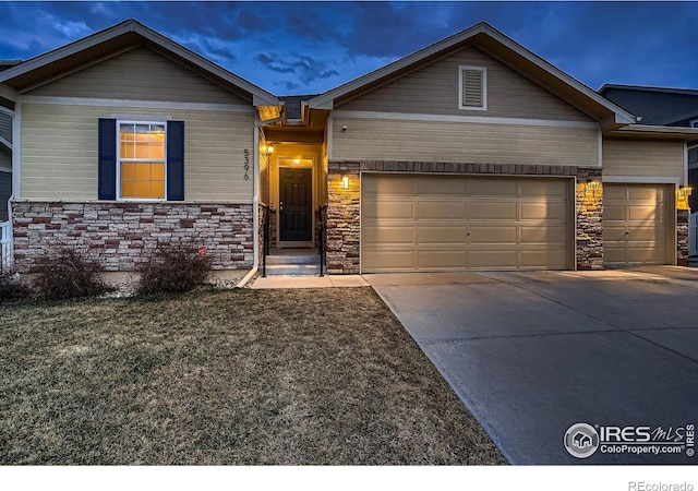 view of front of house with a garage, stone siding, and driveway