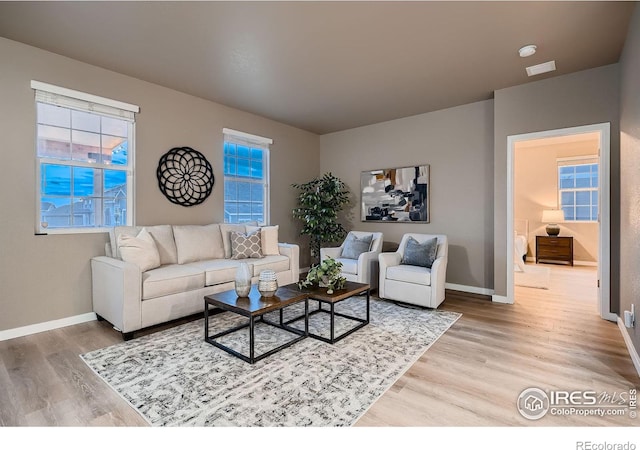 living area featuring baseboards and light wood-style flooring