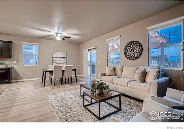 living room featuring baseboards, light wood-style floors, and a ceiling fan