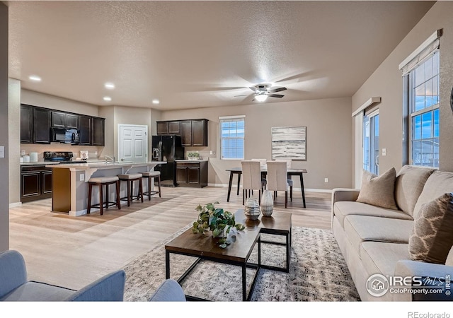 living area with light wood-style flooring, a textured ceiling, recessed lighting, baseboards, and ceiling fan