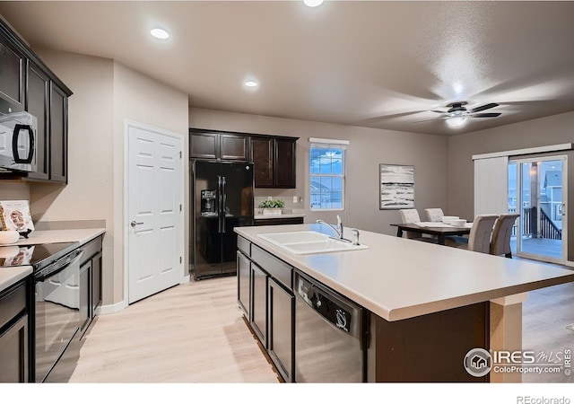 kitchen featuring black appliances, light wood-type flooring, a ceiling fan, and a sink