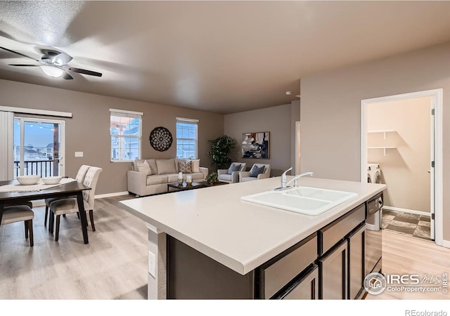 kitchen featuring a sink, light wood-style floors, a ceiling fan, and light countertops