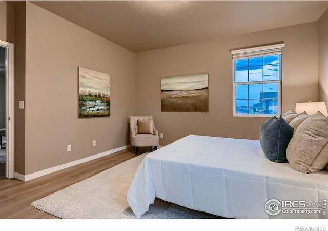 bedroom with baseboards and wood finished floors