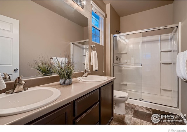 bathroom with double vanity, toilet, a stall shower, and a sink