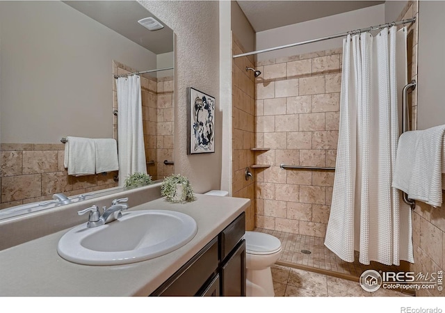 full bath with visible vents, toilet, tiled shower, tile patterned floors, and vanity