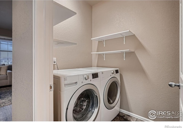 clothes washing area featuring washer and dryer, laundry area, and a textured wall