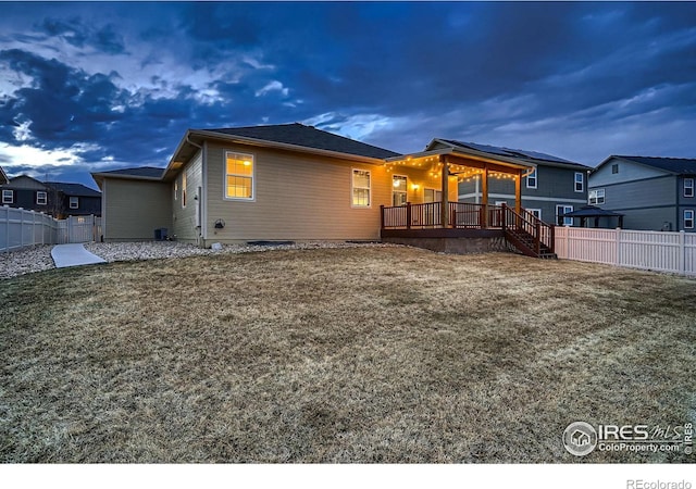 rear view of property with a fenced backyard, a lawn, and a wooden deck