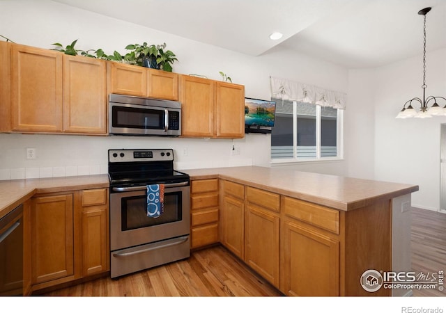 kitchen featuring a peninsula, light wood-style flooring, light countertops, and appliances with stainless steel finishes