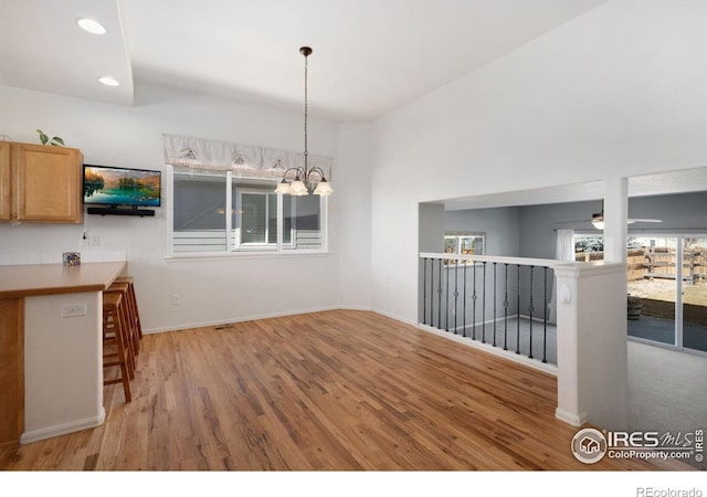 unfurnished dining area featuring ceiling fan with notable chandelier, recessed lighting, wood finished floors, and baseboards