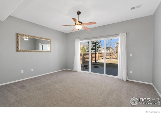 spare room with carpet, a ceiling fan, visible vents, and baseboards