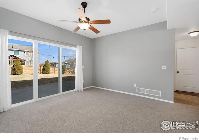 carpeted spare room featuring visible vents, baseboards, and a ceiling fan