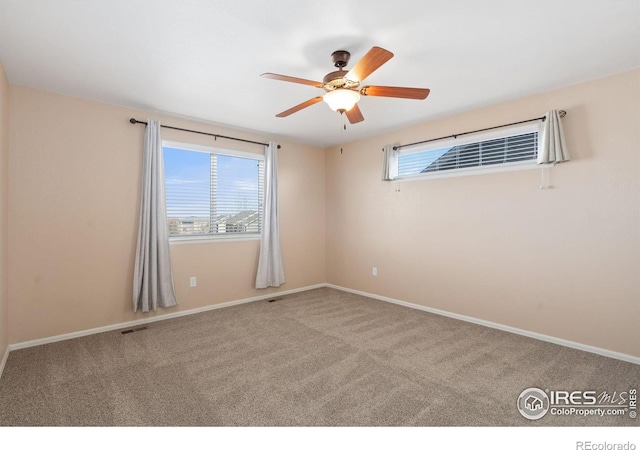 carpeted spare room featuring baseboards, plenty of natural light, and a ceiling fan