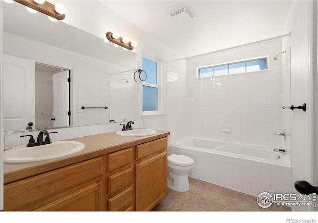 bathroom featuring tiled shower / bath combo, double vanity, visible vents, and a sink